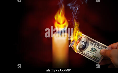 Hand mit einem brennenden 100 Dollar bill Geld mit einem bösen Blick flame Kerze in den Hintergrund. Stockfoto