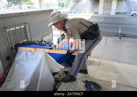 Ein Texas Abteilung für öffentliche Sicherheit State Trooper arbeitet eine obdachlose Lager unter einer Autobahnbrücke in Austin, Texas, zu löschen. Texas reg. Greg Abbott bestellt die Bereinigung der Obdachlosen Bereiche an 17 Standorten in der Gegend von Austin. Stockfoto