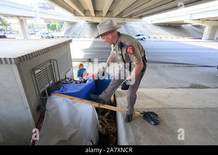 Ein Texas Abteilung für öffentliche Sicherheit State Trooper arbeitet eine obdachlose Lager unter einer Autobahnbrücke in Austin, Texas, zu löschen. Texas reg. Greg Abbott bestellt die Bereinigung der Obdachlosen Bereiche an 17 Standorten in der Gegend von Austin. Stockfoto