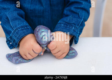 Kind zerknüllt Schleim. In der Nähe der Hände. Der Schleim. Blue Magic glitter Schleim auf einem weißen Hintergrund. Stockfoto