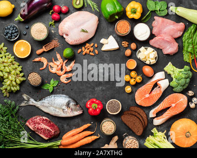 Fodmap Diät Konzept mit Kopie Platz im Zentrum. Niedrige fodmap Zutaten - Geflügel, Fleisch, Fisch, Meeresfrüchte, Gemüse und Obst auf dunklem Hintergrund. Top View oder flach. Stockfoto