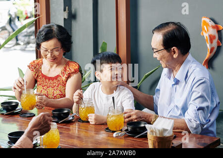 Glückliche kleine vietnamesische Jungen genießen Zeit mit Großeltern im Cafe Stockfoto