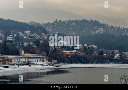 Winter Szene mit gefrorenen See, schneebedeckten Berge, Lichtung, Wald- und Wohnviertel von bulgarischen Dorf Pancharevo, Sofia, Bulgarien Stockfoto