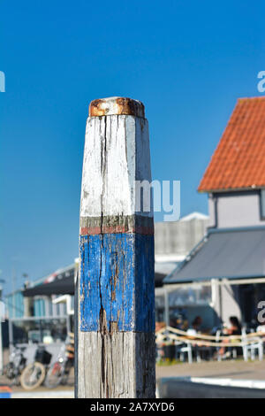 Hölzerne Stange mit alten angebrochen blaue und weiße Farbe zur Befestigung der Boote im Hafen Oudeschild vor blauem Hintergrund Stockfoto