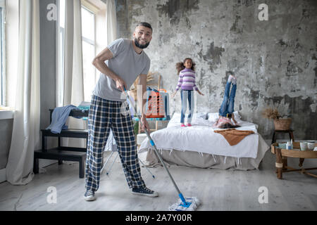 Mann Reinigung der Schlafzimmer und Töchter Spaß Stockfoto