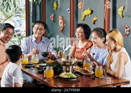 Gerne großen asiatischen Familie reden, lachen und Essen gutes Essen zum Abendessen Stockfoto