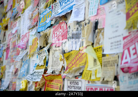 KHARKOV, UKRAINE - OKTOBER 2, 2019: Grunge Message Board mit vielen Werbung. Menschen Verbreitung von Werbung und Informationen auf weißem Papier als pos Stockfoto