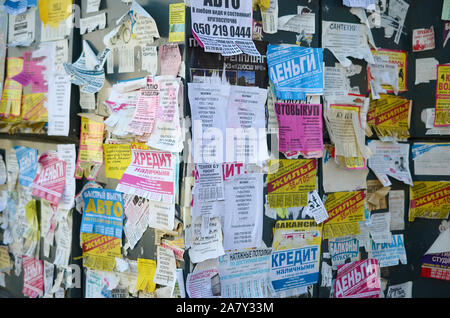 KHARKOV, UKRAINE - OKTOBER 2, 2019: Grunge Message Board mit vielen Werbung. Menschen Verbreitung von Werbung und Informationen auf weißem Papier als pos Stockfoto