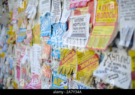 KHARKOV, UKRAINE - OKTOBER 2, 2019: Grunge Message Board mit vielen Werbung. Menschen Verbreitung von Werbung und Informationen auf weißem Papier als pos Stockfoto