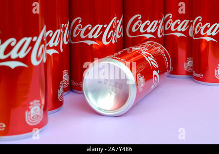 KHARKOV, UKRAINE - OKTOBER 2, 2019: Coca-Cola Logo auf Aluminiumdosen und auf Licht lila Hintergrund platziert. Die meisten berühmten Soda drink Produkt comp Stockfoto