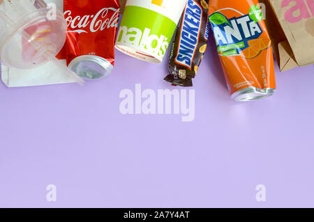 KHARKOV, UKRAINE - OKTOBER 2, 2019: Snickers Schokoriegel verpacken liegt mit leeren roten Coca Cola und Orange Fanta Dosen neben mcdonalds Papier ba Stockfoto