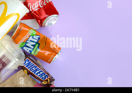 KHARKOV, UKRAINE - OKTOBER 2, 2019: Snickers Schokoriegel verpacken liegt mit leeren roten Coca Cola und Orange Fanta Dosen neben mcdonalds Papier ba Stockfoto