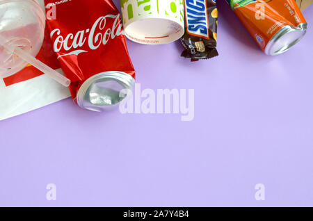 KHARKOV, UKRAINE - OKTOBER 2, 2019: Snickers Schokoriegel verpacken liegt mit leeren roten Coca Cola und Orange Fanta Dosen neben mcdonalds Papier ba Stockfoto