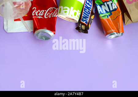 KHARKOV, UKRAINE - OKTOBER 2, 2019: Snickers Schokoriegel verpacken liegt mit leeren roten Coca Cola und Orange Fanta Dosen neben mcdonalds Papier ba Stockfoto