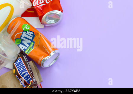 KHARKOV, UKRAINE - OKTOBER 2, 2019: Snickers Schokoriegel verpacken liegt mit leeren roten Coca Cola und Orange Fanta Dosen neben mcdonalds Papier ba Stockfoto