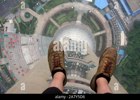 Füße von einem Mann in Shorts auf den Glasboden des Oriental Pearl Tower in Shanghai, Volksrepublik China Stockfoto