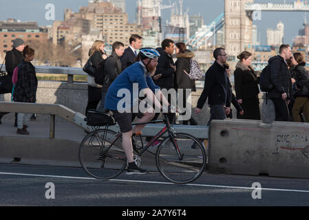 Pendler, die zu Fuß und ein Radfahrer auf der London Bridge während der abendlichen Hauptverkehrszeit, London, UK. Stockfoto