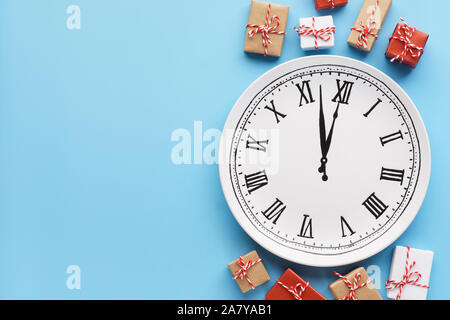 Geschenkboxen rund um einen Teller Uhr auf hellblauem Hintergrund. Neues Jahr oder Heiligabend Konzept. Kopieren Sie Platz. Stockfoto