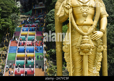 (Selektive Fokus) einen atemberaubenden Blick auf den Lord Murugan Statue im Vordergrund und Touristen klettern eine bunte Treppe, die zu den Batu Höhlen Stockfoto