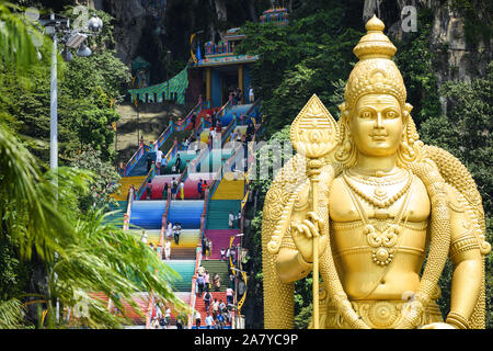 (Selektive Fokus) einen atemberaubenden Blick auf den Lord Murugan Statue im Vordergrund und Touristen klettern eine bunte Treppe, die zu den Batu Höhlen Stockfoto