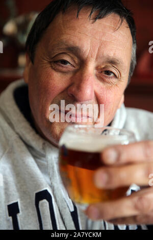 Älterer Mann trinkt Lagerbier in einem Glas. Stockfoto