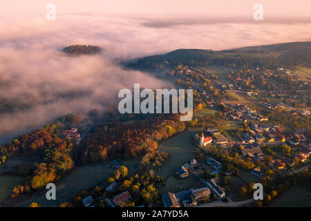 Kleine Stadt Dorf während der Sunrise mit Nebel. von Hügeln in Niederösterreich umgeben. Antenne drone Foto Stockfoto