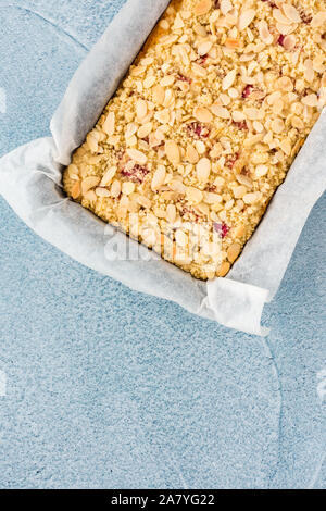 Rhabarber Kuchen in einem Backblech und Blau konkreten Hintergrund mit Kopie Raum bröckeln. Ansicht von oben. Stockfoto