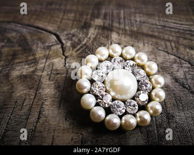 Brosche mit White Pearl für Kleidung auf hölzernen Hintergrund isoliert. Brosche mit Diamanten Stein. Alte kostbare Brosche Stockfoto