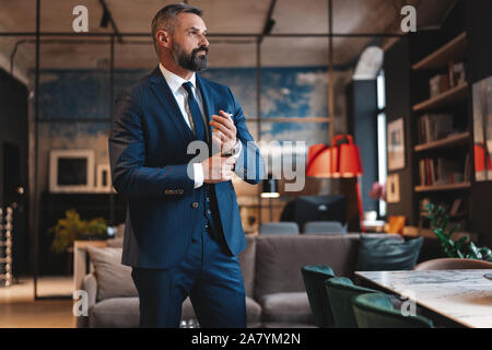 Stilvolle bärtiger Mann im Anzug stand in modernen Büro Stockfoto
