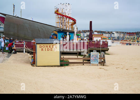 Ansicht der typisch britischen Küste Aktivitäten wie Eselreiten, swing Boote und Helter Skelter am Strand von Weymouth Dorset England Stockfoto