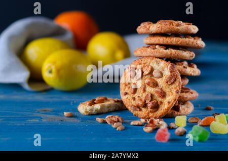 Runde orange Biscuits mit bunten kandierte Früchte und ein Stück saftige Orange liegen auf einem Holztisch Stockfoto