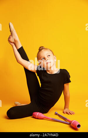 Wenig gymnast stretching Bein in der Nähe von Stäbe während des Trainings Stockfoto