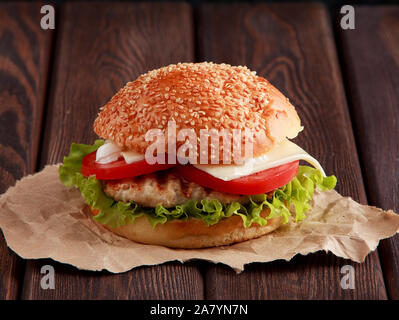 Hausgemachte Hamburger mit Salat, Käse auf dem Holztisch und Papier Stockfoto