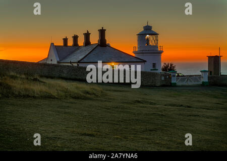 Swanage, Dorset England Schöne orange leuchten, kurz vor Sonnenaufgang, an Amboss Point Lighthouse Stockfoto