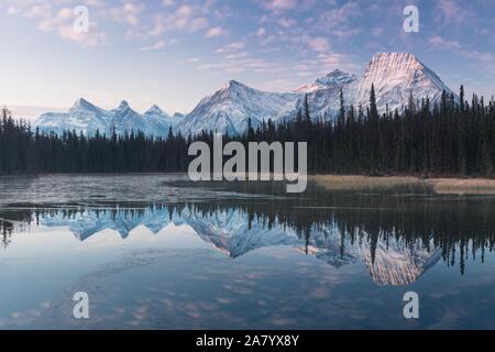 Nahezu perfekte Reflektion der Rocky Mountains in den Bow River. In der Nähe von Canmore, Alberta, Kanada. Jahreszeit der Winter kommt. Bear Country. Stockfoto