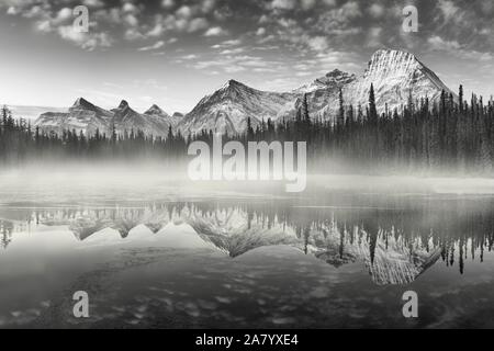 Nahezu perfekte Reflektion der Rocky Mountains in den Bow River. In der Nähe von Canmore, Alberta, Kanada. Jahreszeit der Winter kommt. Bear Country. Stockfoto