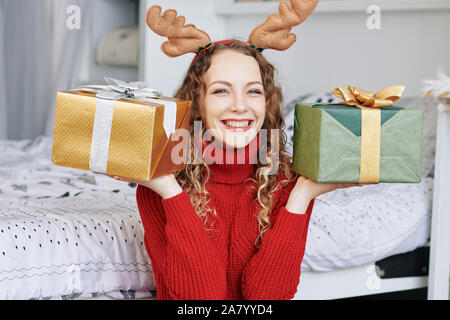 Portrait von Happy neugierige junge Frau, zwei Geschenke sie für Freunde gewickelt Stockfoto