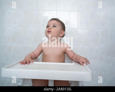 1 Jahr alte Hündin Baby sitzt auf einem hohen Stuhl warten auf Ihre Mahlzeit Stockfoto