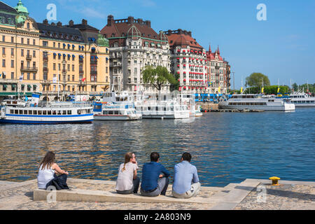 Waterfront Stockholm, Rückansicht von Freunden im Sommer Entspannung entlang der Kais im Hafen Nybrokajen im Zentrum von Stockholm, Schweden. Stockfoto