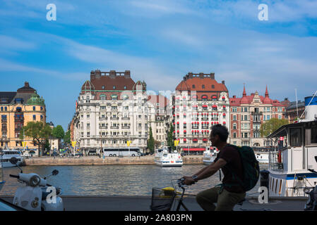 Man radfahren Stadt, Blick auf einen Mann, Radfahren entlang Nybrokajen im Hafen der Stadt Bereich der Blasieholmen/Ostermalm Viertel von Stockholm. Stockfoto