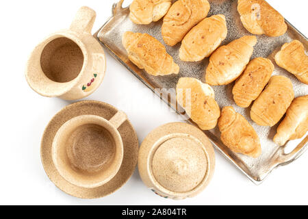 Menge ganz, frisch gebackene Mini Croissant auf Tablett mit Schale, Sugar Bowl und Keramik Kanne flatlay auf weißem Hintergrund Stockfoto