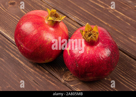 Gruppe von zwei ganze Frische rote Granatapfel auf braunem Holz Stockfoto