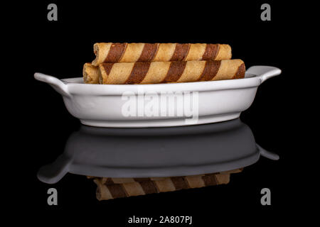 Gruppe von drei ganzen crunchy beige Haselnuss gerollte Waffel Keks in weiße, ovale Keramik Schüssel auf schwarzem Glas isoliert Stockfoto