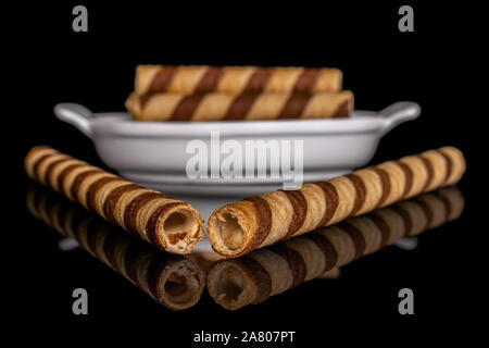 Gruppe von fünf ganze crunchy beige Haselnuss gerollte Waffel Keks in weiße, ovale Keramik Schüssel auf schwarzem Glas isoliert Stockfoto