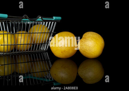 Gruppe von fünf ganze Frische gelbe Pflaume im Warenkorb auf schwarzem Glas isoliert Stockfoto
