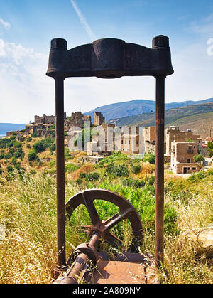 Alten verrosteten Mechanismus mit großen Zahnrad und das mittelalterliche Dorf Vathia in der Mani, Griechenland. Stockfoto