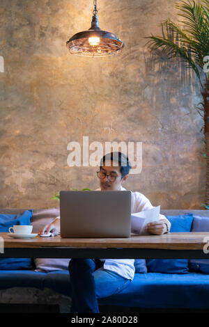 Man Rechnungen bezahlen auf seinem Laptop mit Kaffee auf den Tisch im Café. Stockfoto