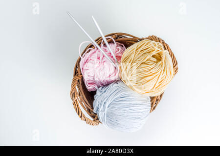 Pastellfarbenen Strang der Thread für das Stricken und Stricknadeln in einem kleinen Korb. Handarbeit Hintergrund. Auf weissem Hintergrund Kopie Raum Stockfoto