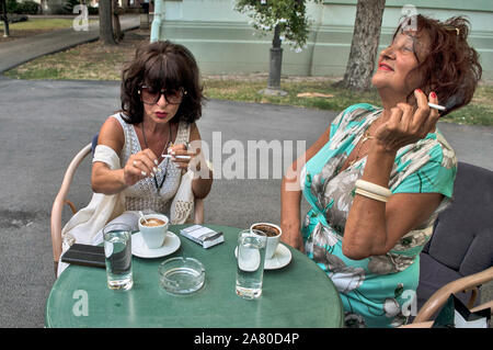 Treffen an einem Sommergarten Restaurant mit zwei Frauen über Kaffee und Zigaretten. Sie haben sich schon seit langer Zeit gesehen. Stockfoto