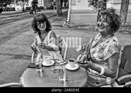 Treffen an einem Sommergarten Restaurant mit zwei Frauen über Kaffee und Zigaretten. Sie haben sich schon seit langer Zeit gesehen. Stockfoto